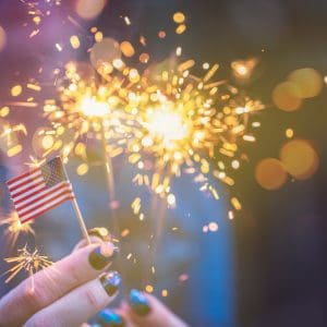 Hand holding sparkler and American flag