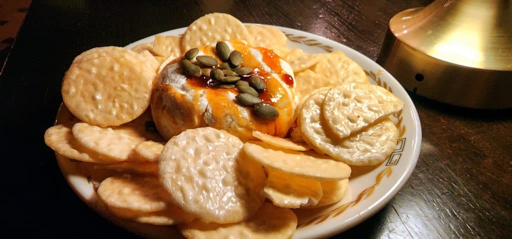 Baked cheese with crackers and pumpkin seeds.