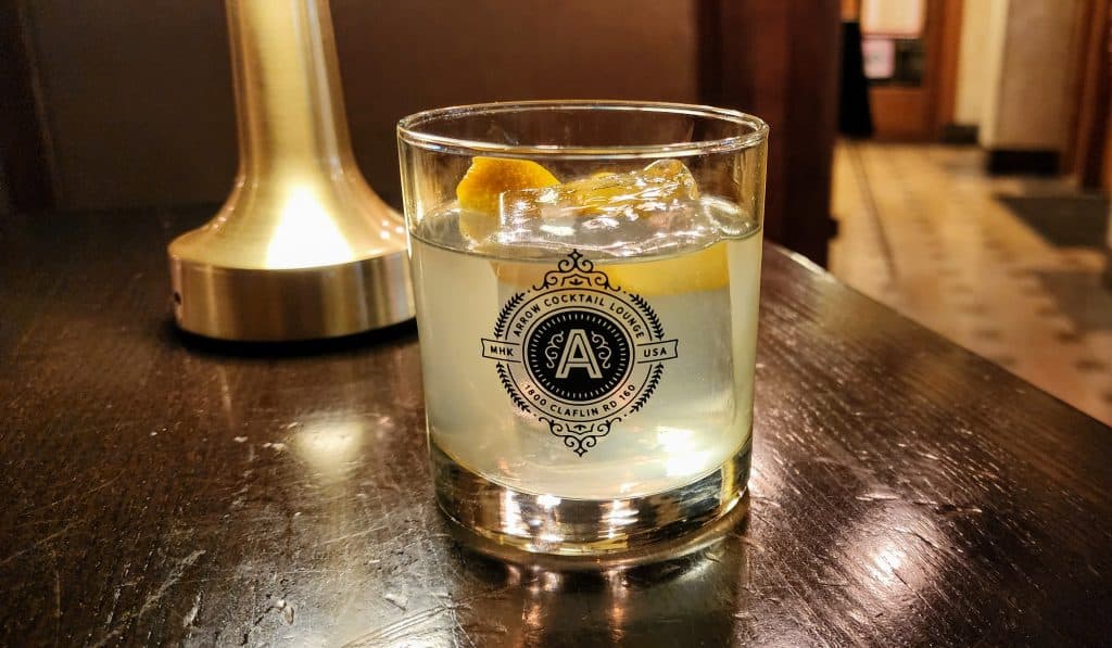 Cocktail with lemon on table, ambient lighting.