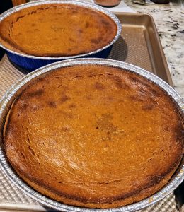 Two freshly baked pumpkin pies on kitchen counter.