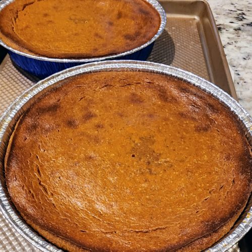 Two freshly baked pumpkin pies on kitchen counter.