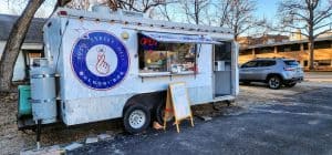 A food truck is parked in front of a house.