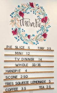 A menu board for a bakery with a floral wreath on it.