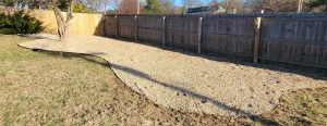 A backyard with a gravel path and a fence.