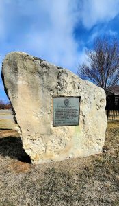 A large rock with a plaque in front of it.