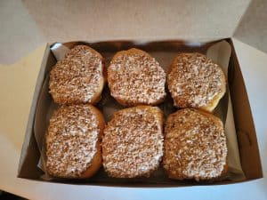 Five donuts in a box on a table.