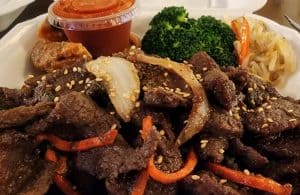 A plate of beef and vegetables on a table.