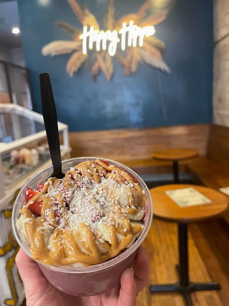 A person holding a bowl of food in front of a restaurant.
