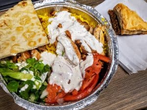 A plate of gyro, salad, and pita on a table.