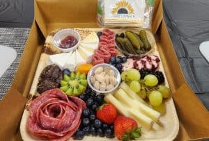 A box with a variety of meats, cheeses, fruits and nuts.