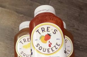 Three bottles of tre's squeeze on a wooden table.