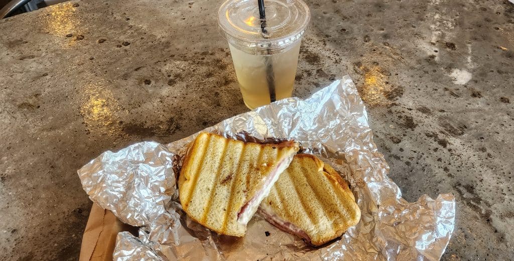 A sandwich on a piece of foil next to a drink.