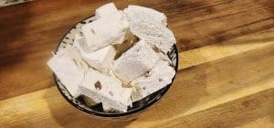 Bowl of homemade nougat on wooden table.