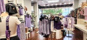 A purple clothing store with clothes hanging on racks.