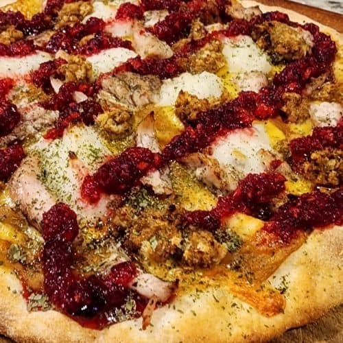 Handmade pizza with toppings on wooden surface.