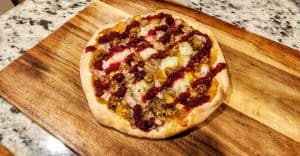 Homemade sausage and cranberry pizza on wood board.