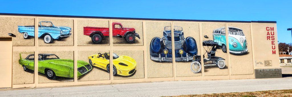 Colorful car murals on museum exterior wall.