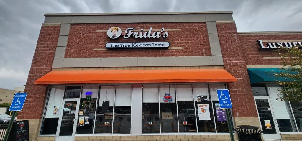 The front of a restaurant with an orange awning.