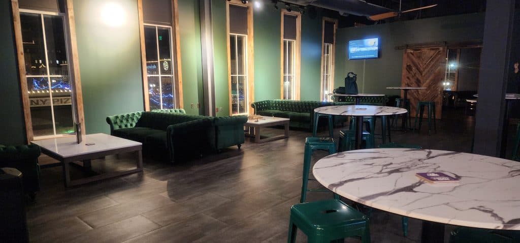 The Sinkers Lounge in Manhattan is a stylish room adorned with green couches and tables.