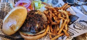 In Aggieville Brewing Company, an appetizing burger and fries are sitting on a table in Manhattan, KS.