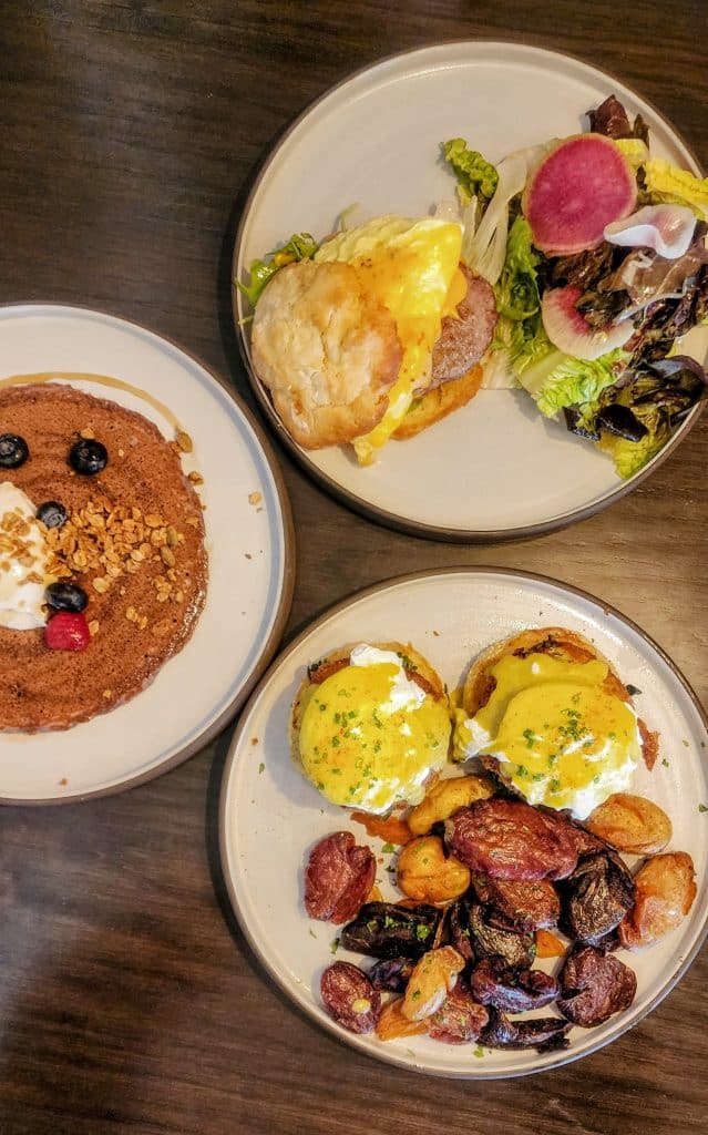 Three plates of food on a wooden table.