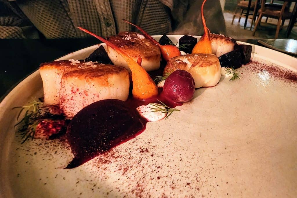 A plate of scallops and vegetables.