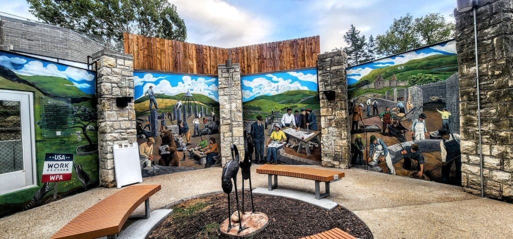 A mural of people working on a wall at Sunset Zoo in Manhattan, KS.