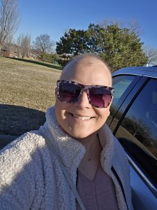 A woman wearing sunglasses in front of a car.