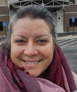 A smiling surgeon with a warm scarf, enjoying a chilly day outdoors.