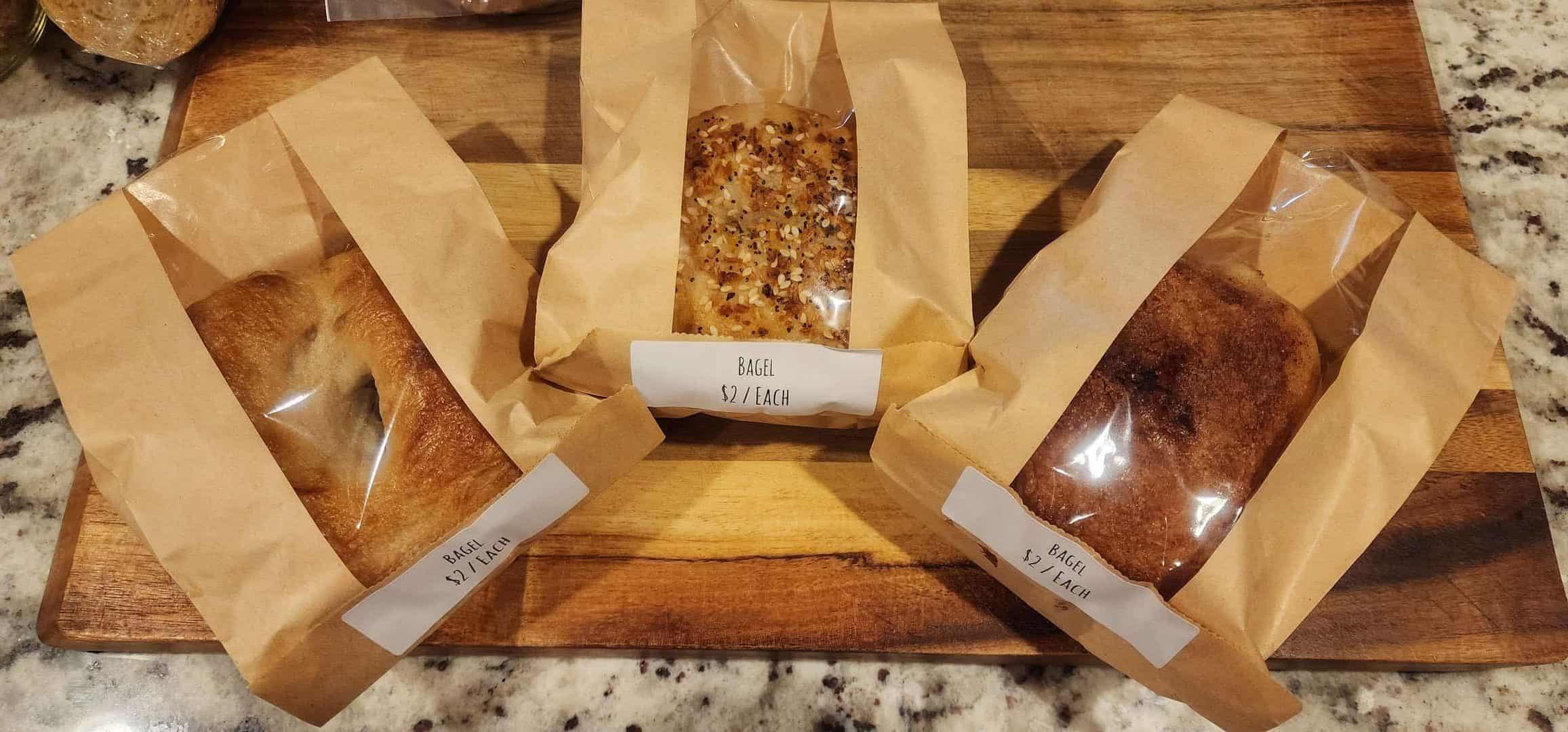 Products that you can buy from Homestead on Dogwood. A glass jar of sourdough bread crumbs, a whole chicken, and sourdough bagels.