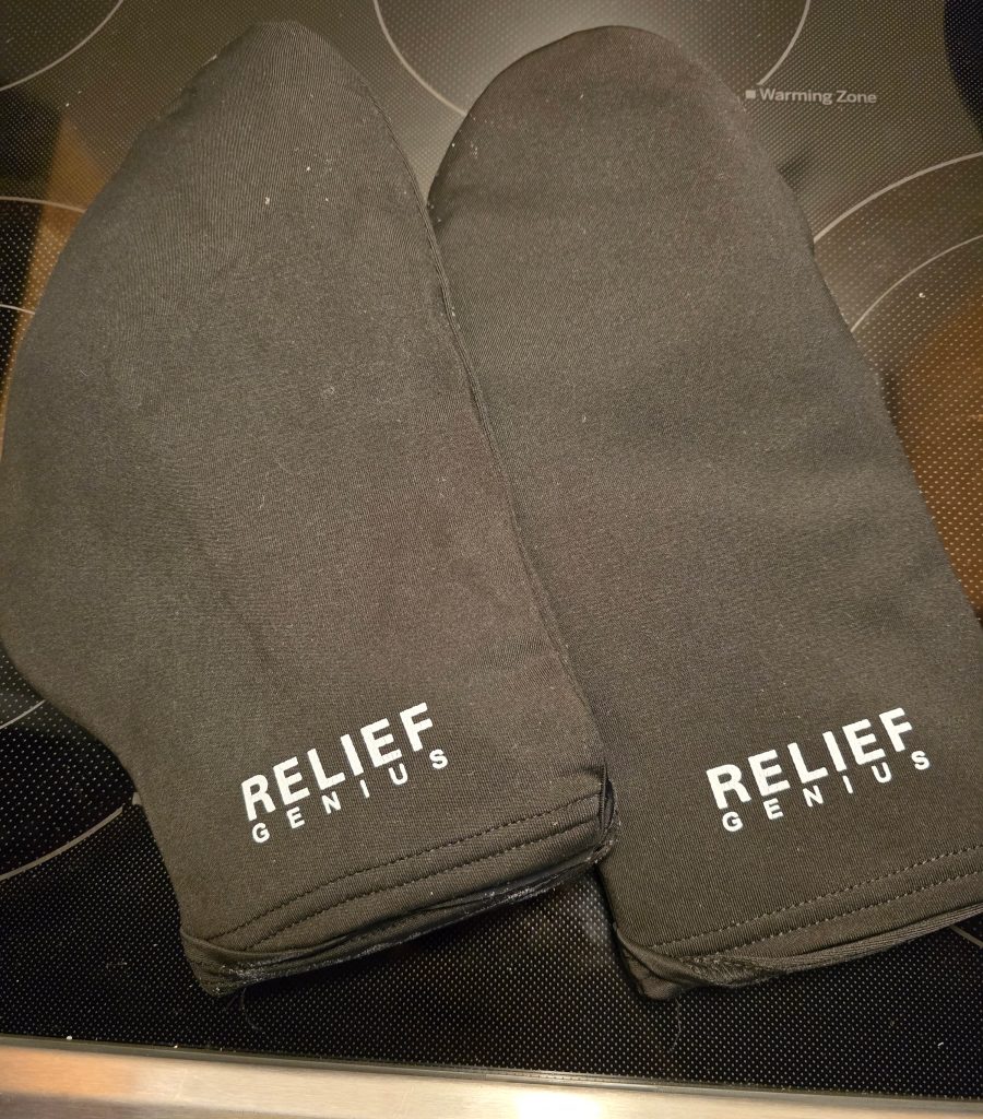 Two black oven mitts with the text "RELIEF GENIUS" on them are placed on a stovetop. The surface, showing visible circular outlines of electric burners, makes it easier to see where pots and pans should go.
