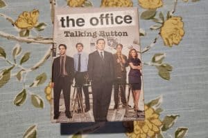 A box labeled "The Office Talking Button" presents the perfect gift idea, showing a group of people in office attire standing in a line against a floral background, bringing joy and laughter to any scene.