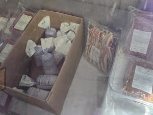 A freezer from Simon Meat Locker in Olsburg, KS, containing packaged meat products&mdash;including vacuum-sealed cuts and stacked bacon&mdash;showcases expert meat processing with each item clearly labeled by product and weight.